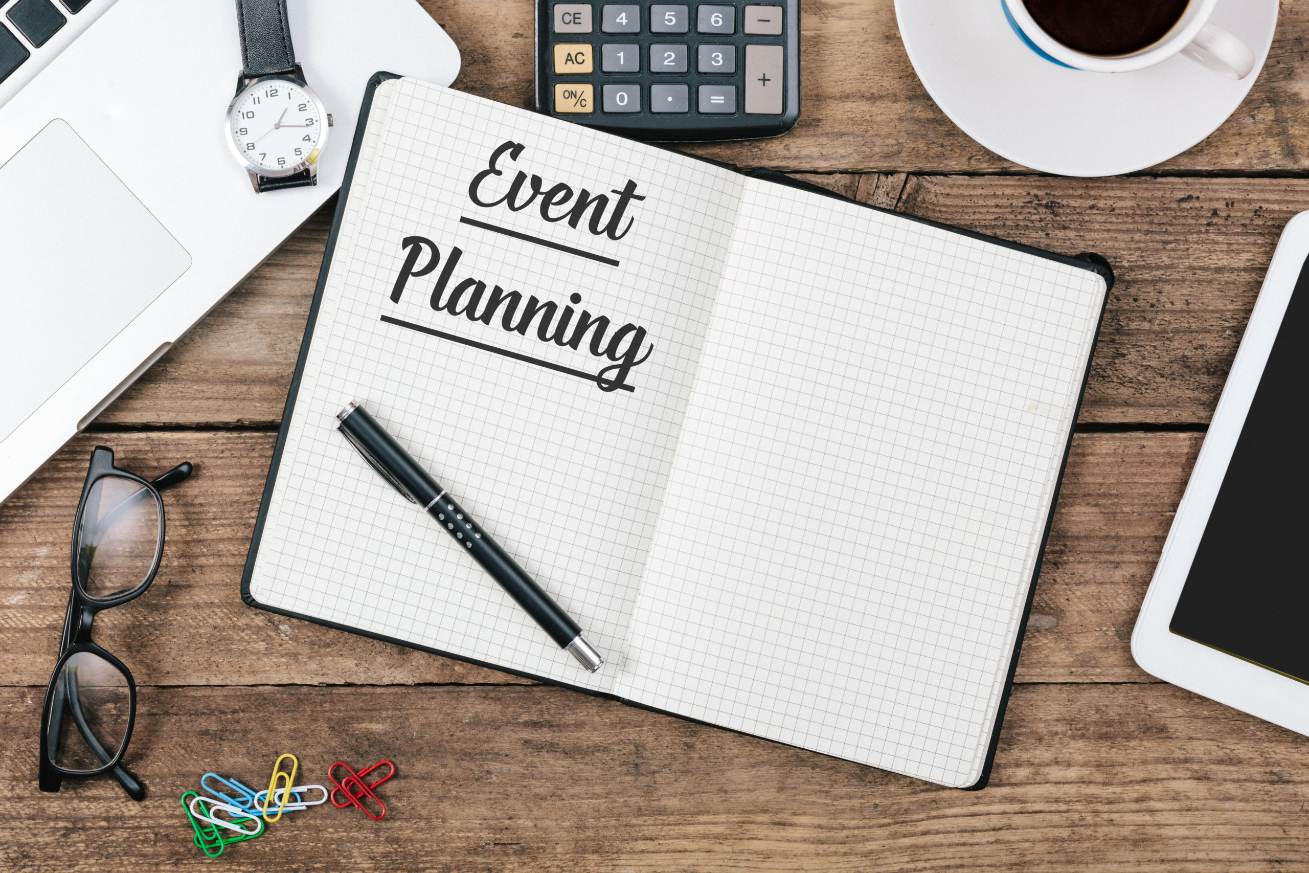 An event planning notebook is on a desk, opened, with a pen.