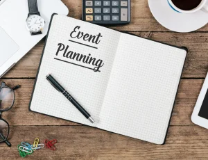 An event planning notebook is on a desk, opened, with a pen.